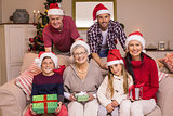 Portrait of a happy extended family in santa hat holding gifts
