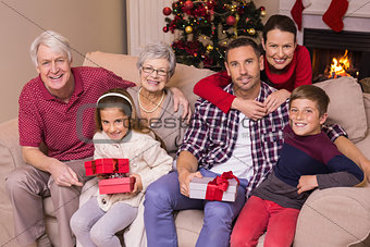 Multi generation family holding gifts on sofa