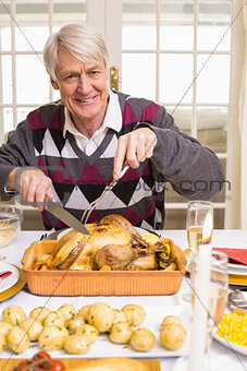 Portrait of a grandfather carving roast turkey at christmas