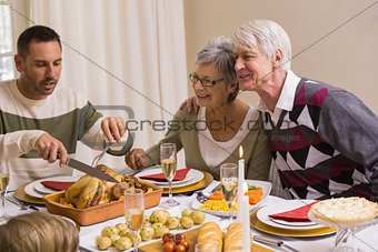 Man carving chicken during christmas dinner