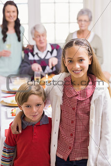 Brother and sister smiling at camera in front of their family
