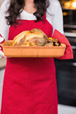 Mid section of woman holding roast turkey