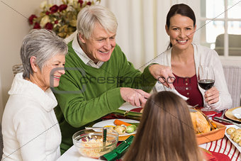 Smiling grandfather carving chicken during christmas dinner