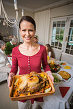 Portrait of a smiling woman showing the roast turkey