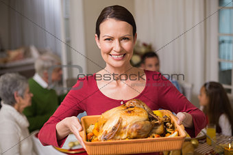 Pretty woman showing the roast turkey in front of her family