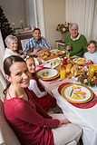 Festive family smiling at camera during christmas dinner