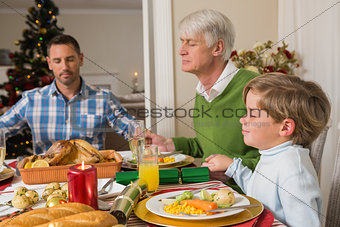 Extended family saying grace before christmas dinne
