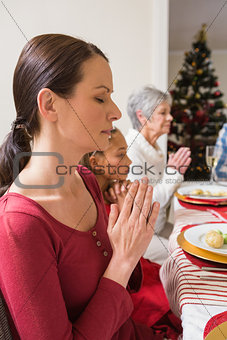 Extended family praying before christmas dinner