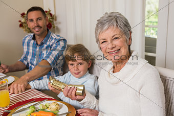 Smiling family pulling christmas crackers at the dinner table