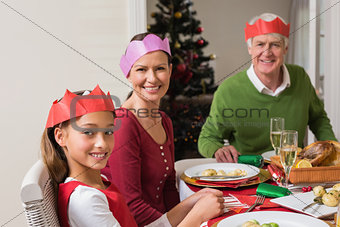 Smiling extended family in party hat at dinner table