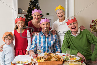 Happy extended family in party hat at dinner table