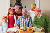 Cheerful extended family in party hat at dinner table
