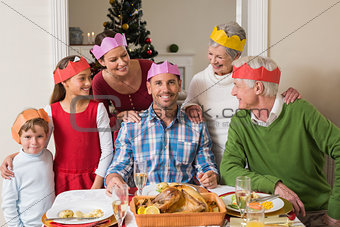 Cheerful extended family in party hat at dinner table