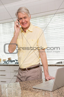 Senior man using his laptop on the phone