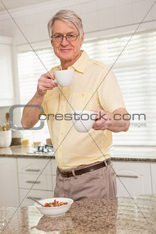 Senior man offering cup to camera