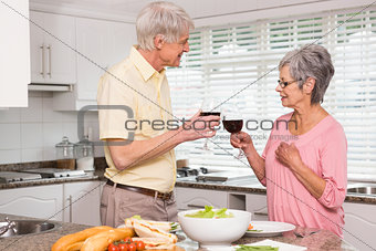 Senior couple preparing lunch together having red wine