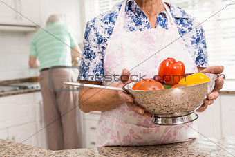 Senior woman showing colander of vegetables