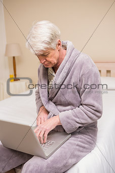 Senior man using laptop on bed