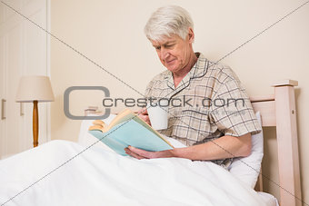 Senior man reading a book in bed