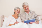 Senior couple relaxing in bed using tablet pc