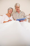 Senior couple relaxing in bed using tablet pc