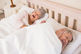 Senior man blocking out his wifes snoring