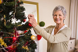 Senior woman decorating the christmas tree