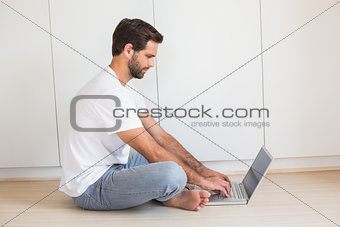 Happy man using laptop on floor