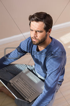 Depressed man sitting on floor using laptop