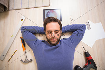 Casual man lying on floor surrounded by his diy tools