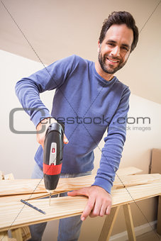 Casual man drilling hole in plank