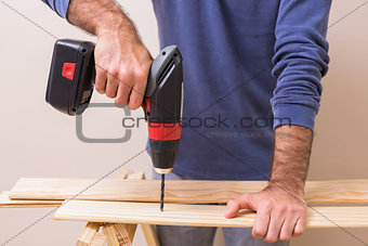 Casual man drilling hole in plank