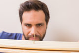 Casual man looking at nail in plank