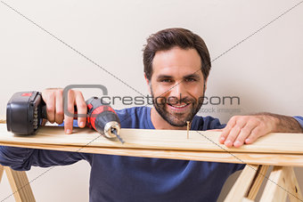 Casual man drilling nail in plank
