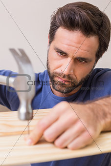 Casual man hammering nail in plank