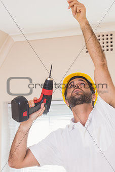 Construction worker drilling hole in ceiling