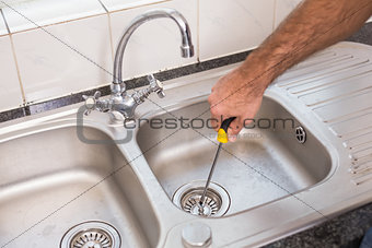 Man fixing sink with screwdriver