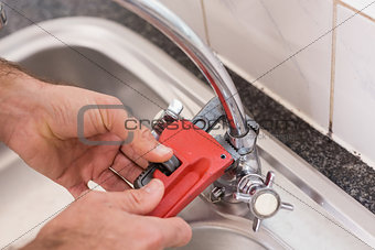 Man fixing tap with tool