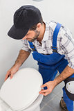 Plumber installing lid on toilet