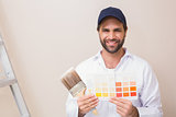 Painter holding a colour chart smiling at camera