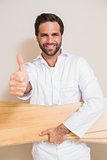 Carpenter holding planks showing thumbs up