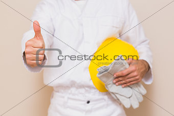 Handyman holding his yellow helmet showing thumbs up