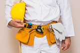 Handyman holding his yellow helmet in tool belt