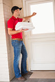 Delivery man holding pizza while knocking on the door