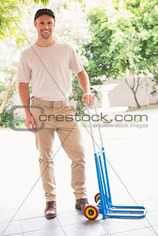 Happy delivery man leaning on trolley