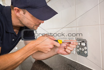 Electrician unscrewing face plate of plug socket