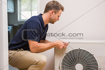 Focused handyman fixing air conditioning