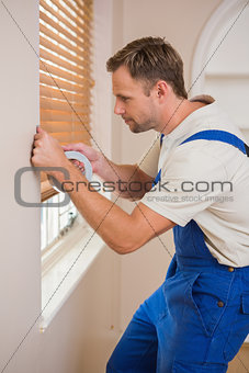 Man puting silver duct tape on the corners of the wall