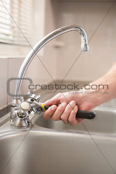 Man fixing tap with pliers