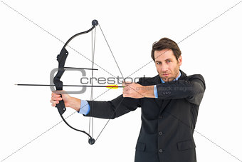 Serious businessman practicing archery looking at camera